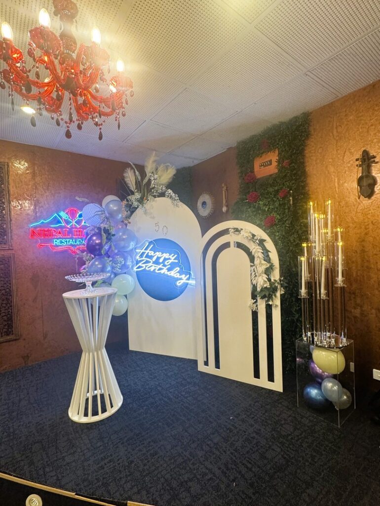 Modern birthday stage backdrop with balloons, florals, and neon sign by Saraya D Decor Adelaide